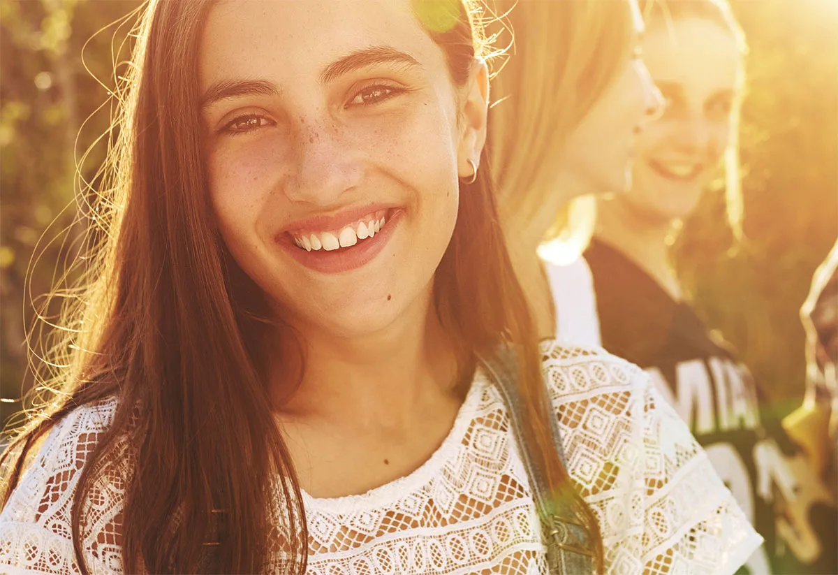 A girl smiles confidently, surrounded by peers, symbolizing support in a Virtual Intensive Outpatient program for mental health