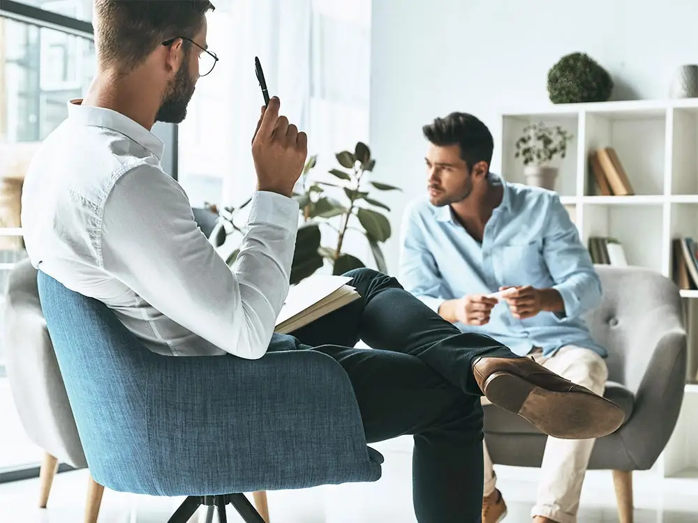 Two men seated in chairs during Obsessive Compulsive Disorder treatment.